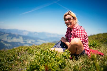 Kitzbüheler-Alpen-Hero-Wandern-Elke-Henke-genießt-eine-Pause-inmitten-von-Moosbeeren-am-Lodron-c-Daniel-Gollner