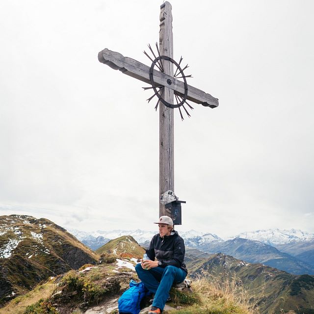Kitzbüheler Alpen Hero wandelen Nik Brandstätter vanaf het kruis op de bergtop geniet hij van het uitzicht over de Kitzbüheler Alpen c Daniel Gollner