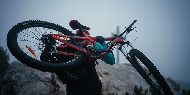 Kitzbüheler Alpen Hero Bike Ben Kalra trägt sein Mountainbike auf den Gipfel im PillerseeTal c Daniel Gollner